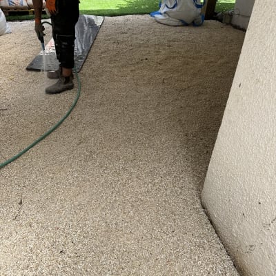 אדם משקה חצץ עם צינור גינה באתר שיפוץ