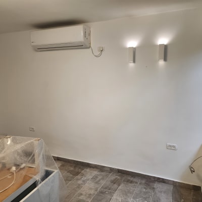 קיר צבוע בלבן עם כיסוי פלסטיק על רהיטים