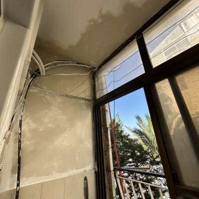 קיר ותקרה עם סימני צבע ותיקונים ליד חלון