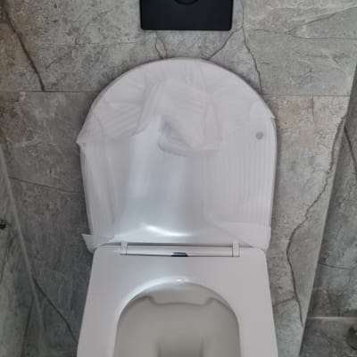 אסלה עם מכסה פתוח ומנגנון הדחה על הקיר