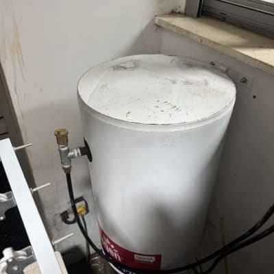 דוד שמש לבן ליד חלון עם צינורות וחיבורים