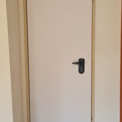 דלת לבנה עם ידית שחורה ומסגרת בהירה