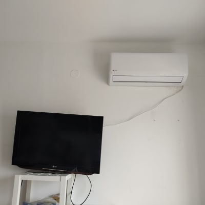 מזגן מותקן על קיר לבן עם כבל חשמל