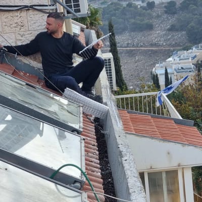 אדם מתקין דוקרנים נגד יונים על גג