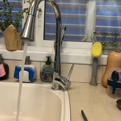 ברז מטבח נירוסטה עם מים זורמים בכיור לבן