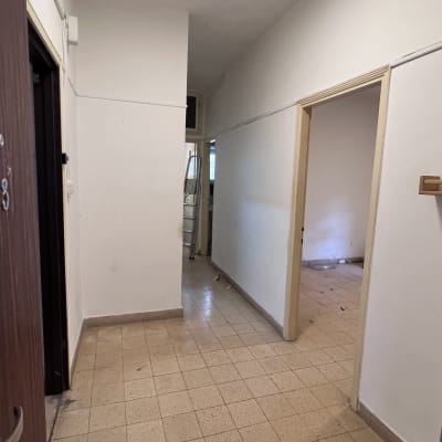 מסדרון ריק עם דלתות פתוחות וסולם ברקע