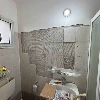 שיפוץ קיר אמבטיה עם כלים וחומרים על הכיור