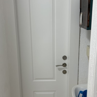 דלת לבנה עם ידית מתכת ליד כיור קטן