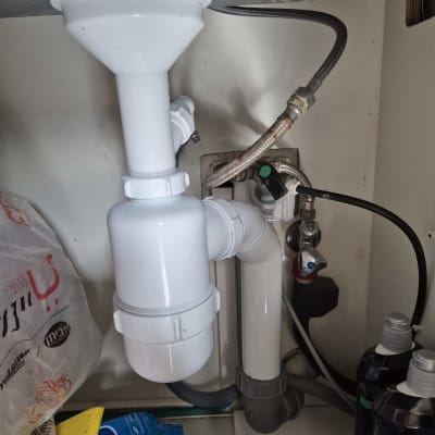 צנרת פלסטיק לבנה מתחת לכיור עם חיבורים