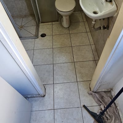 חדר אמבטיה עם רצפה מלוכלכת, מטאטא ומטלית