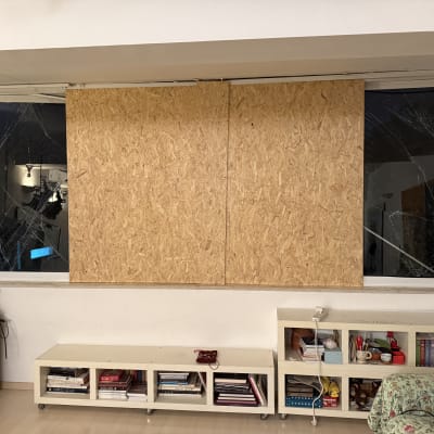 חלון שבור מכוסה בלוח עץ, מדפים עם ספרים