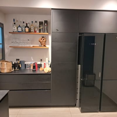 מטבח מאורגן עם מדפים, בקבוקים ומקרר שחור