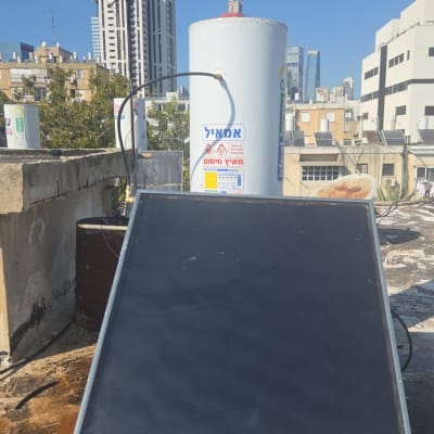 דוד שמש על גג עם קולטים ומבנים ברקע