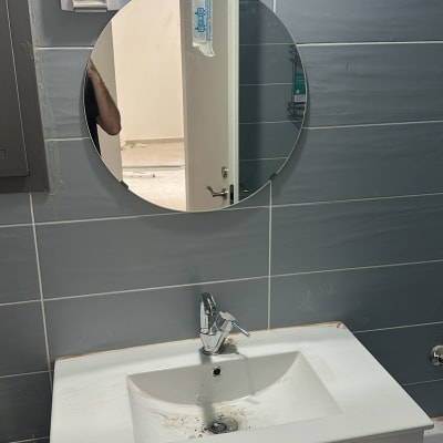 מראה עגולה מעל כיור בחדר אמבטיה