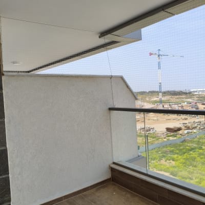 רשת יונים מותקנת במרפסת עם נוף לבנייה