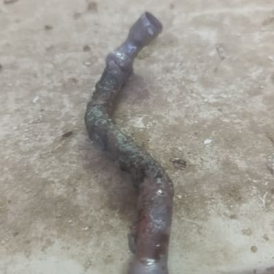 צינור מתכת ישן ומעוקל על שולחן עבודה