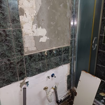 צנרת חשופה בקיר חדר אמבטיה עם תיקוני טיח