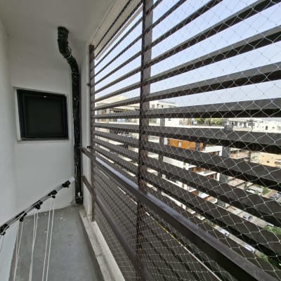 רשת יונים מותקנת על מרפסת עם נוף עירוני