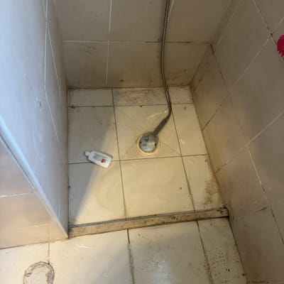 רצפת מקלחת עם לכלוך ובקבוק חומר ניקוי