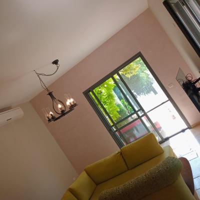 קיר צבוע בצבע ורוד בהיר בסלון עם ספה צהובה