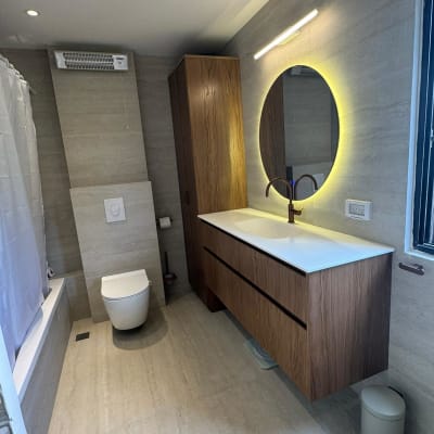 חדר אמבטיה עם כיור עץ ומראה עגולה מוארת