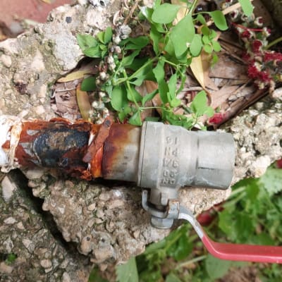 ברז מתכת חלוד עם ידית אדומה על רקע בטון