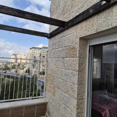 מרפסת עם קיר אבן ומעקה מתכת