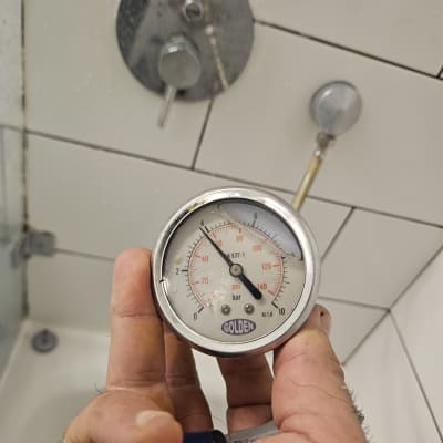 בדיקת לחץ מים בצנרת באמצעות שעון לחץ בחדר רחצה
