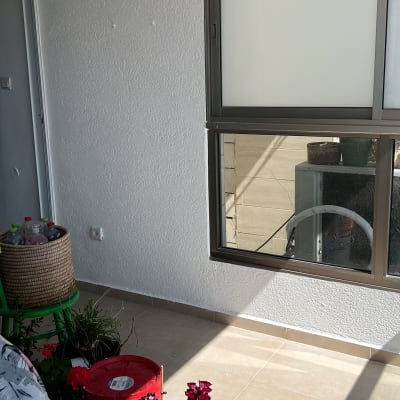 דלי צבע אדום על הרצפה ליד קיר לבן