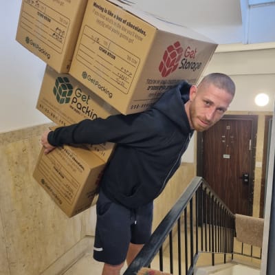 אדם נושא קופסאות קרטון במדרגות בניין