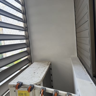 יחידת מיזוג אוויר מותקנת ליד חלון עם תריסים