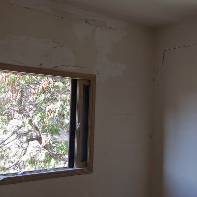 קירות עם סדקים ותיקוני צבע ליד חלון