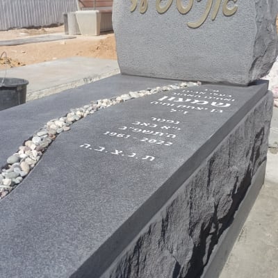 מצבה עם כיתוב בעברית ואבנים קטנות