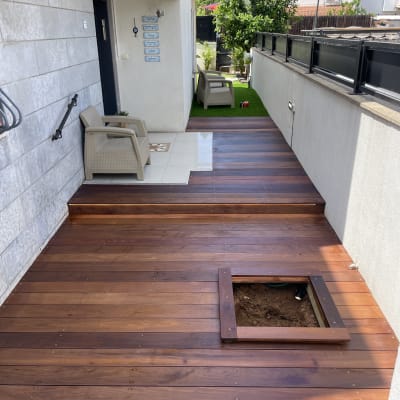 דק עץ עם פתח מרובע לאדמה בגינה