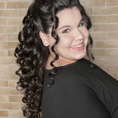 אישה עם תסרוקת תלתלים על רקע קיר לבנים