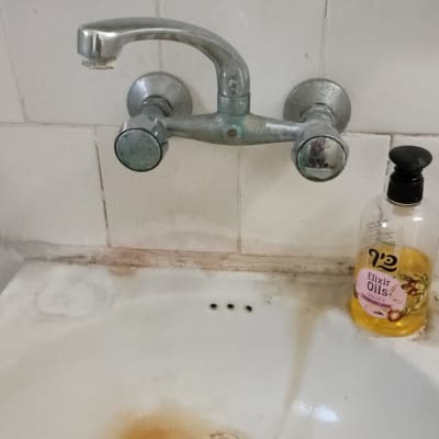 ברז כפול מעל כיור עם כתם חלודה