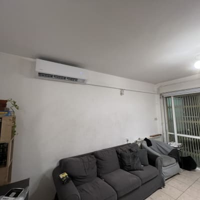 מזגן מותקן על קיר בסלון עם ספה ושולחן