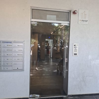 דלת זכוכית עם השתקפות אנשים בכניסה לבניין