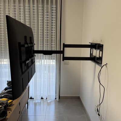 טלוויזיה מותקנת על זרוע קיר בחדר עם וילונות.