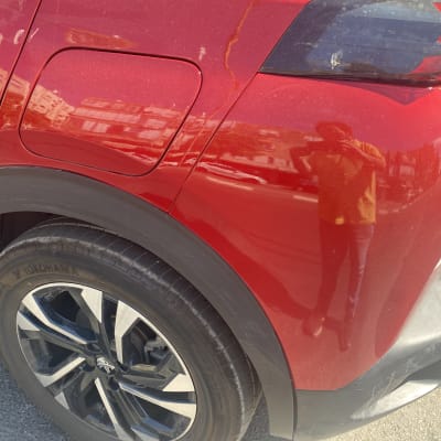 חלק אחורי של רכב אדום עם גלגל וכנף