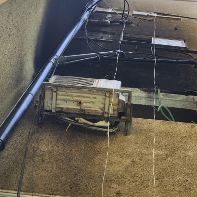 יחידת מזגן חיצונית מותקנת על קיר בניין עם צינורות חשמל