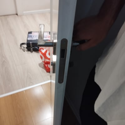 יד אוחזת בידית דלת פתוחה עם רצפת עץ ברקע