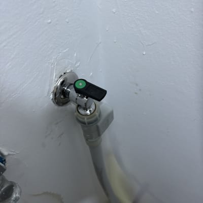 ברז מים עם צינור מחובר לקיר לבן