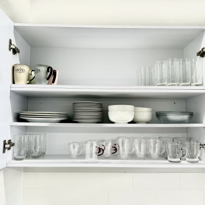ארון מטבח פתוח עם כוסות, צלחות וקערות מסודרים