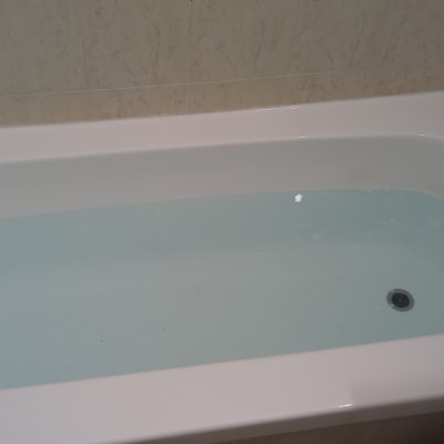 אמבטיה מלאה במים עם ברז מתכת על הקיר