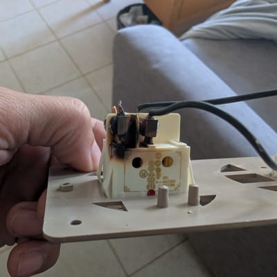 שקע חשמלי עם חוטים שרופים ביד אדם