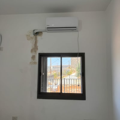 מזגן מותקן על קיר מעל חלון בחדר
