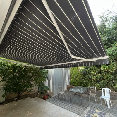 סוכך שחור עם פסים לבנים בחצר מרוצפת