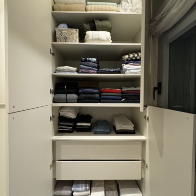 ארון בגדים מסודר עם מדפים מלאים בבגדים מקופלים