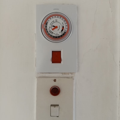 שעון טיימר ומתג חשמלי על קיר לבן